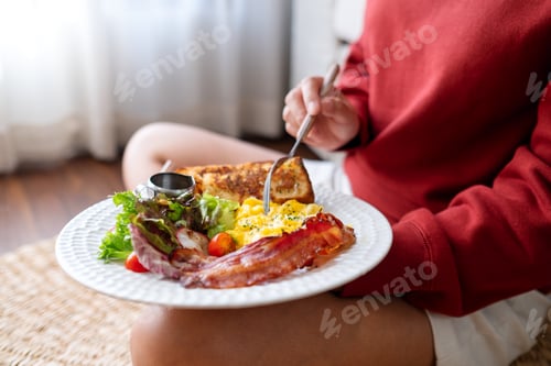 Preview: Closeup image of a young woman eating American breakfast at home