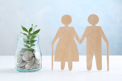 Preview: Pension savings. Figure of senior couple, jar of coins and green twig on white wooden table