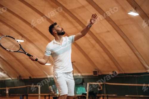 Preview: Side view, game in action. Man is playing tennis indoors in the hangar