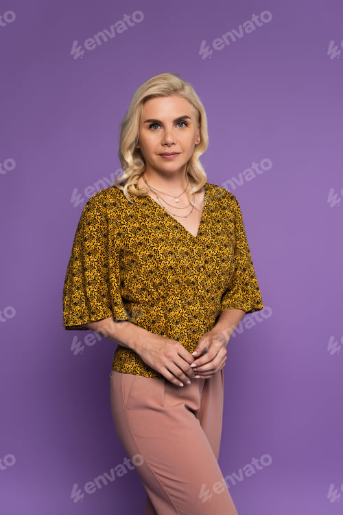 Preview: pretty and blonde woman in blouse posing isolated on purple