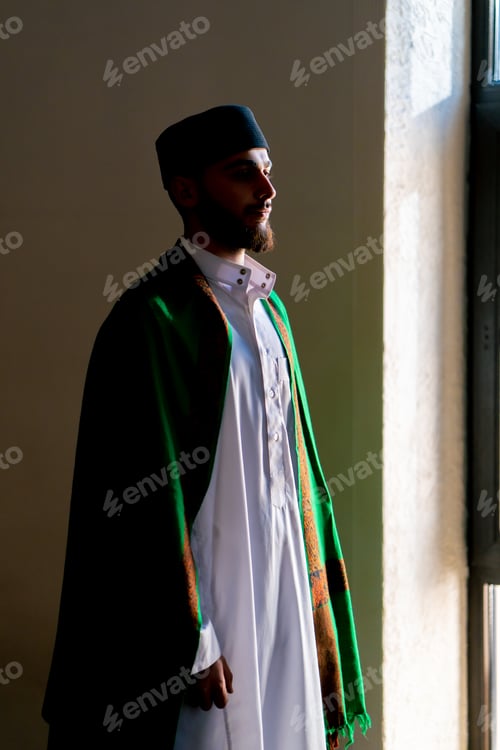 Preview: Silhouette of an Arab priest who stands in a mosque in national clothes and prays to Allah