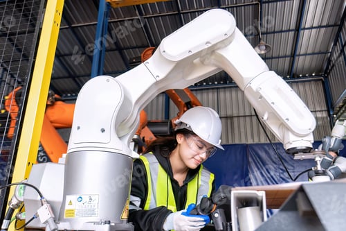 Preview: Young female asian service engineer holding robot controller operate robot arm automation factory