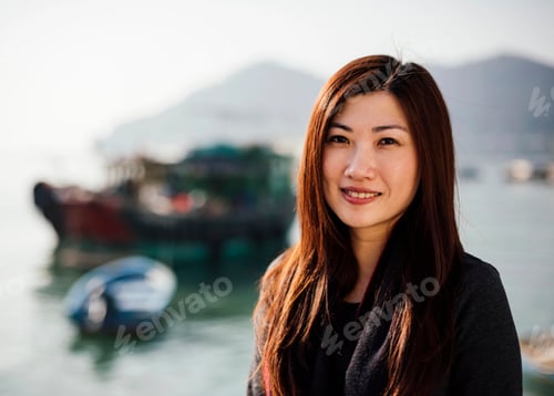 Preview: Portrait of mid adult woman in front of boats on water, looking at camera smiling