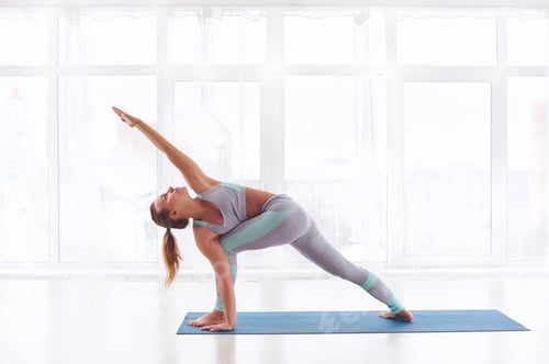 Preview: Beautiful young woman practices yoga asana Parivritta Parshvakonasana - Revolving side angle posture