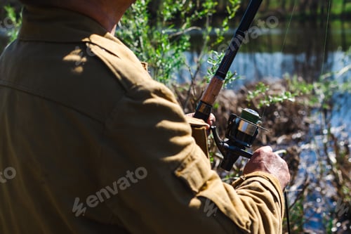 Preview: Close-up of the hand of a male fisherman who spins the reel of the fishing rod to pull the line.