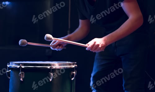 Preview: The drummer plays with mallets on floor tom in dark room.
