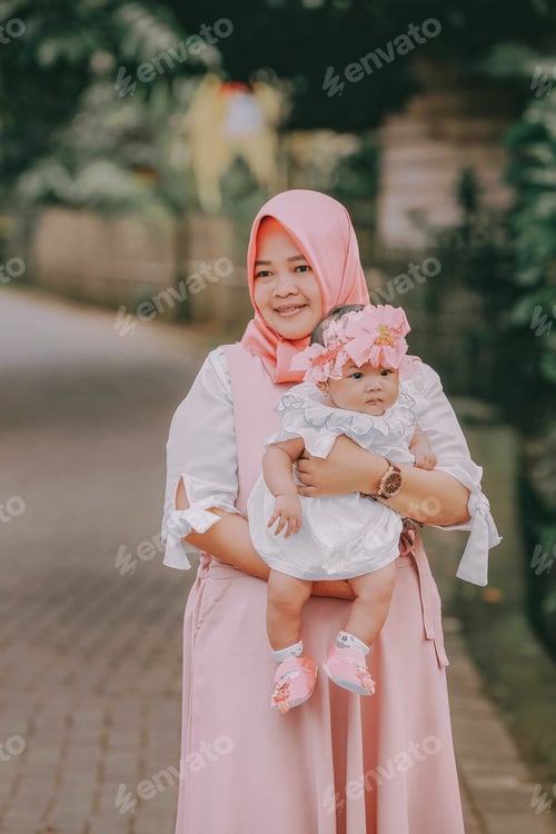 Preview: Woman Holding Baby with Flower Headband Outdoors