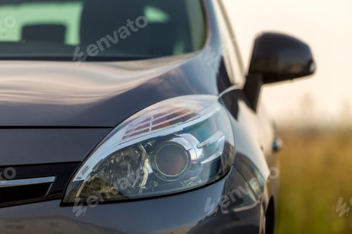 Preview: Close-up detail part of black shiny car-headlight, mirror, hood and radiator grille