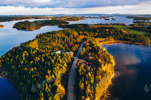 Preview: Aerial view of road through autumn forest with blue lakes in Finland.