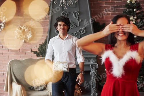 Preview: Two of them is smiling. Woman in red dress will now receive Christmas gift from boyfriend