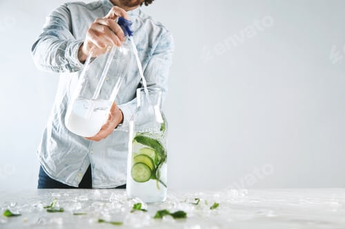 Preview: Bartender pours sparkling water in vintage bottle with ice, cucumber and mint