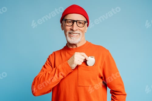 Preview: Happy senior man holding a cardio stimulator over torso, smiling, confidently looking at camera