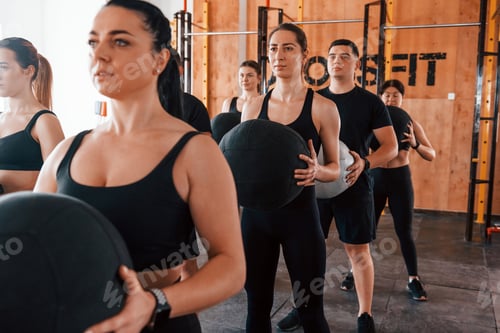 Preview: With fitness balls. Group of young sportive people have crossfit day indoors in gym