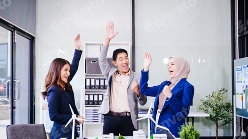 Preview: Three business people celebrate success at their desk, raising hands in congratulations.