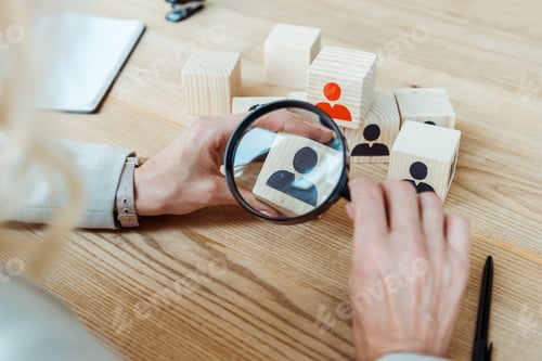 Preview: cropped view of recruiter holding magnifier near wooden cube