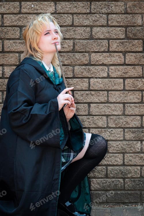 Preview: Blonde Caucasian female cosplayer dressed as a wizard with a magic wand