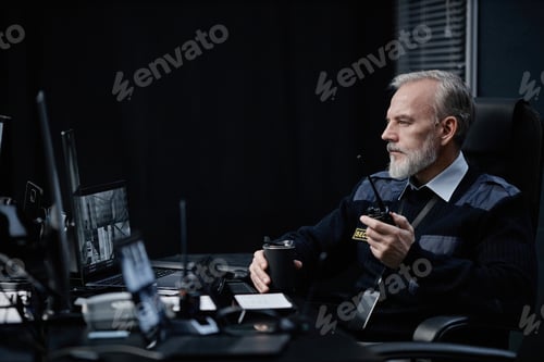 Preview: Middle Aged Caucasian Security Guard Monitoring Surveillance Cameras at Night