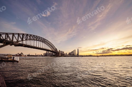 Preview: Bridge crossing a body of water at sunset in Sydney, Australia.