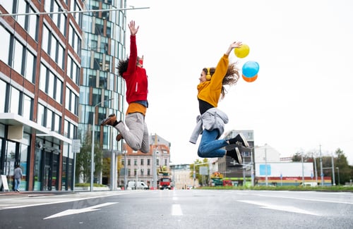 Preview: Young couple with balloons jumping outdoors on street, video for social media concept.