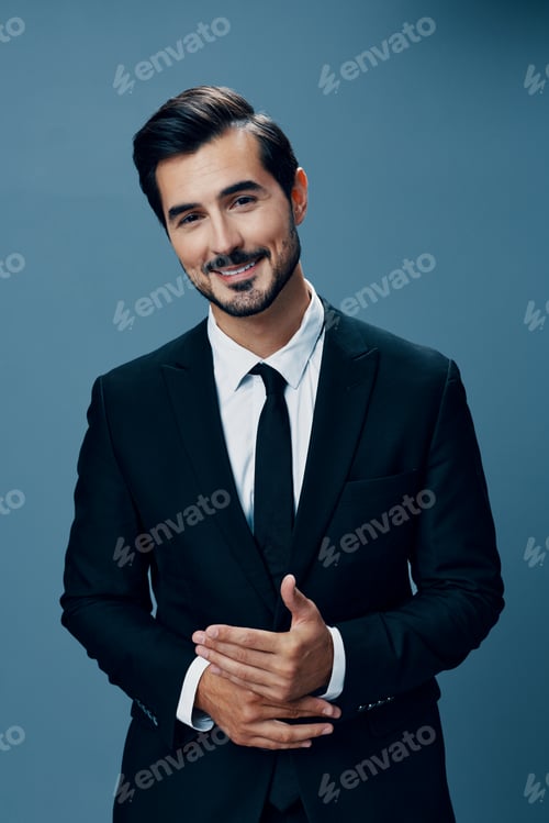 Preview: A business man looks thoughtfully into the camera smiling and rubbing his hands in a black suit