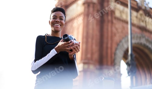Preview: Cheerful young woman taking photos on street