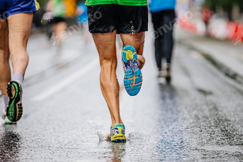 Preview: legs male runner athlete run marathon race on wet asphalt, water drops on sole running shoes