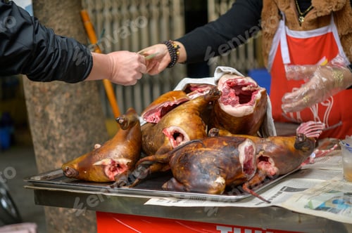 Preview: Roasted dog carcasses placed on a table in front of an anonymous paying buyer at a local Vietnamese