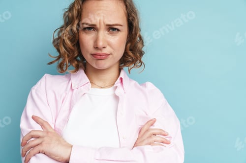 Preview: Young ginger woman frowning while posing with arms crossed