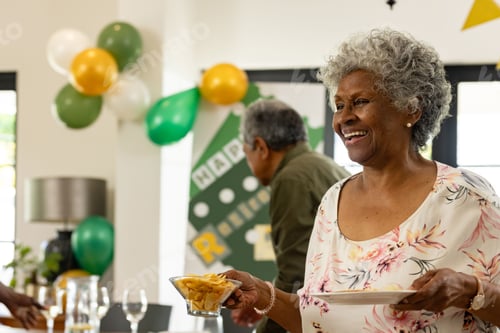 Preview: Elderly woman joyfully serving snacks at retirement celebration with balloons