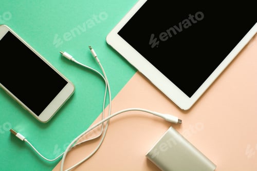 Preview: Smart phone, tablet and power bank on paper background. Recharging concept. Top view. Flat lay.