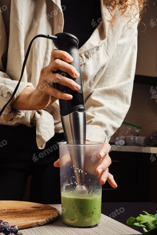 Preview: Unrecognizable woman using blender in the kitchen