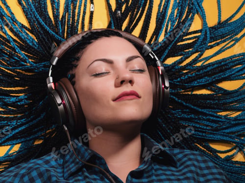 Preview: Beautiful young girl with african blue braids is listening to music with headphones and dancing