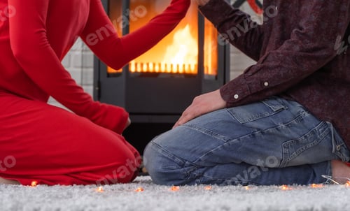 Preview: Man and woman in love date at home are sitting near the fireplace stove