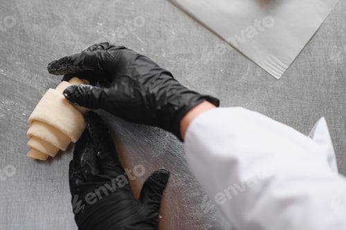 Preview: Baker carefully shaping croissant dough in bakery kitchen