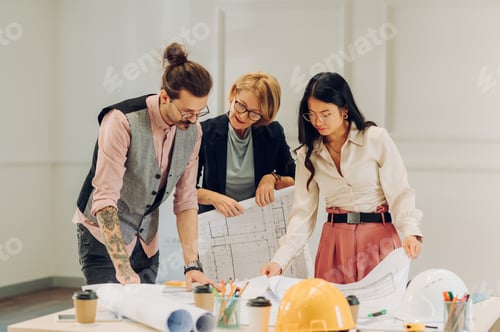 Preview: Multiracial team of architects having a meeting while using blueprints