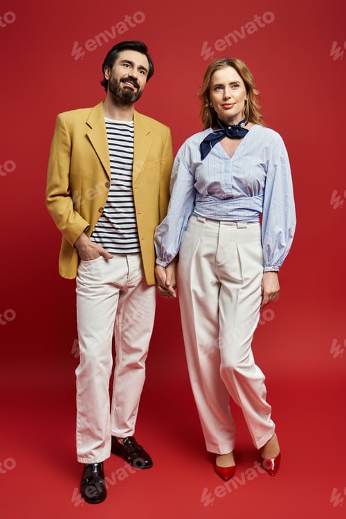 Preview: Stylish middle aged couple poses against vibrant red background in fashionable attire
