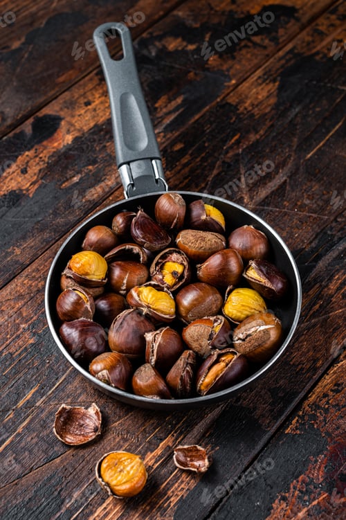 Preview: Roasted chestnuts nuts in a pan. Wooden background. Top view