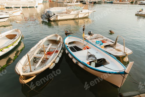 Preview: Small fishing boats floating peacefully in calm harbor waters at golden hour