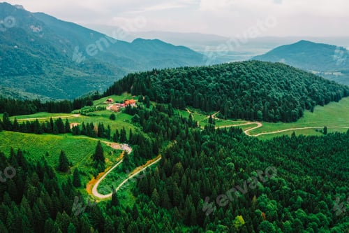Natural drone photography with green forest and a tiny chalet surrounded by mountains and nature