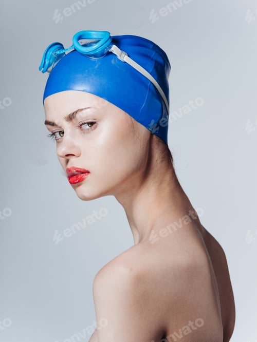 Preview: Portrait of a woman swimmer in a blue cap and glasses on the head bared shoulders