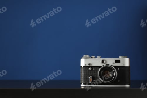 Preview: Vintage camera on wooden table on blue background, space for text