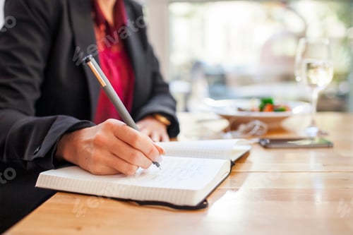 Preview: Midsection of businesswoman writing in book