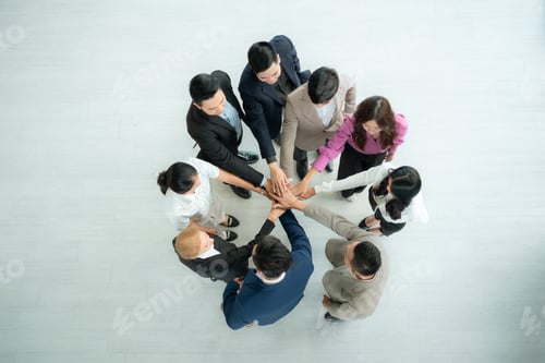 Preview: Top view of group of business people joining hands together in office to empower each other