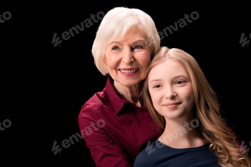 Preview: happy grandchild and grandmother hugging isolated on black in studio