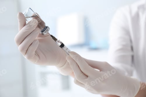 Preview: Doctor filling syringe with medication from vial in hospital, closeup