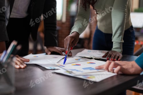 Preview: Closeup of diverse businesspeople analyzing papers with company statistics