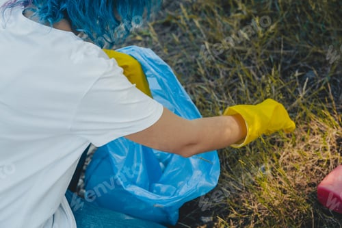Preview: Young female collecting trash and putting in plastic garbage bag - environmental pollution concept