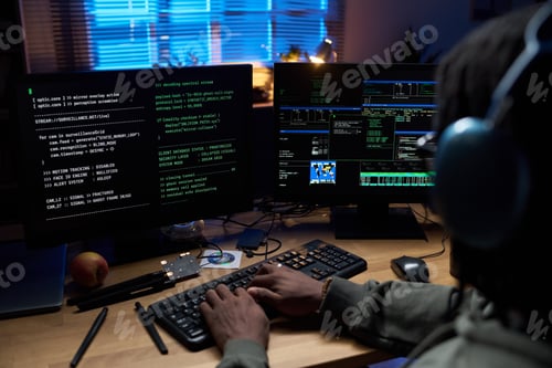 Preview: Young Black Man Coding Software on Computer Monitors at Night