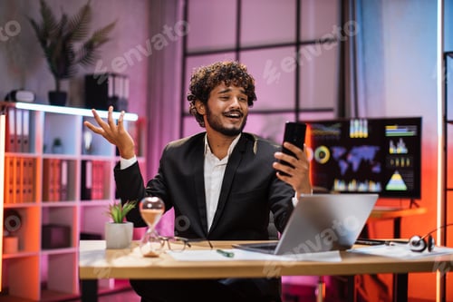Preview: Portrait of smiling bearded businessman having mobile video conversation while sitting at table