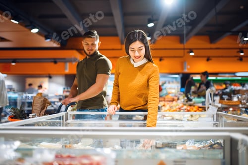 Preview: Family couple at the refrigerator in grocery store